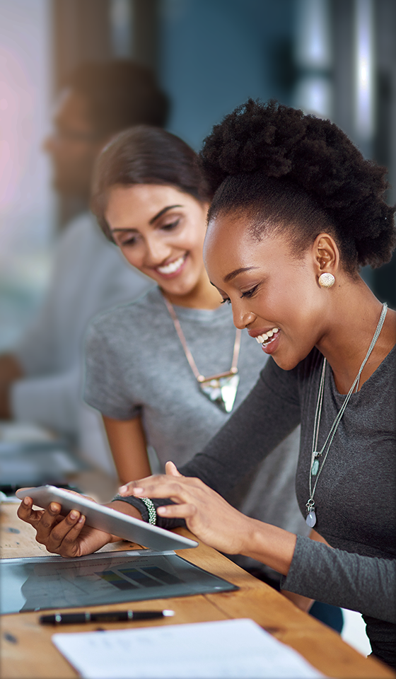 Due donne che sorridono e guardano un iPad