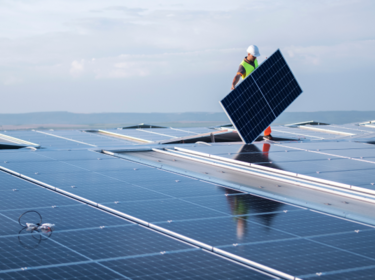 sol-energy-commercial-industrial-solutions-worker-hardhat-holding-solar-panel-rooftop