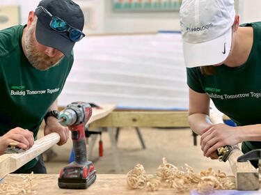 Due dipendenti di Prologis che levigano il legno per un progetto in occasione dell'IMPACT Day